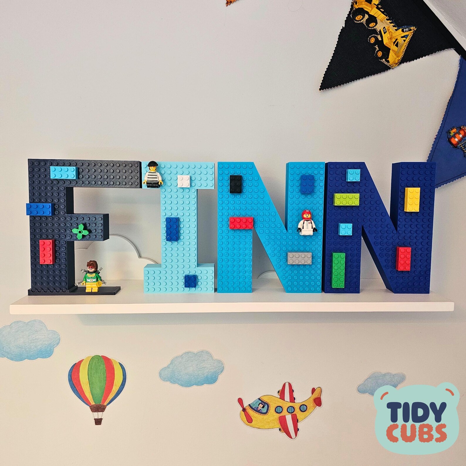 Blue 3D brick letters FINN displayed on a white nursery shelf